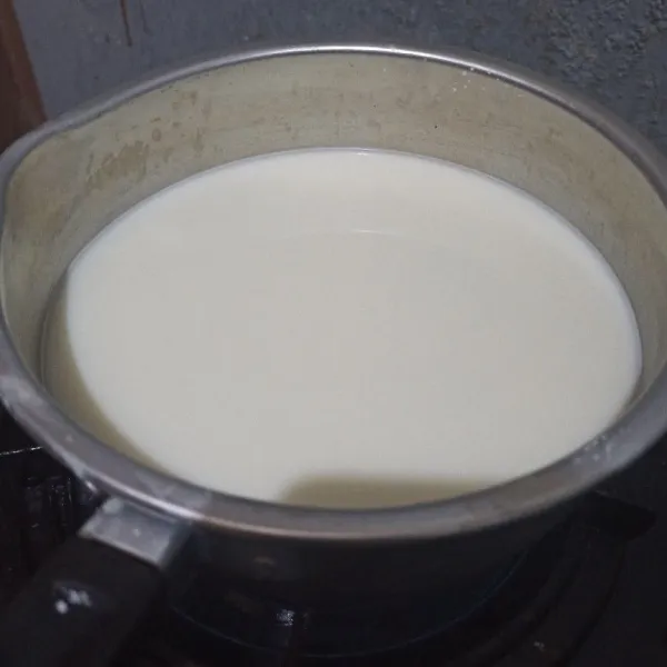 Tuang susu cair ke panci lalu beri larutan susu. Beri garam dan aduk, lalu masak hingga mendidih.