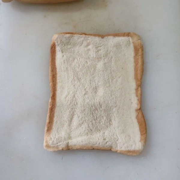 Pipihkan roti dengan rollin pin, kemudian oles dengan susu kental manis.