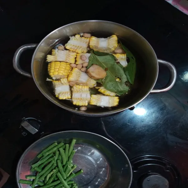 didihkan air dalam panci, lalu masukan daun salam, laos, jagung, labu siam dan kacang tanah, masak 5 menit