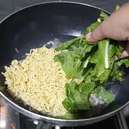 Tambahkan air masak hingga mendidih, lalu masukkan mie dan caisim.