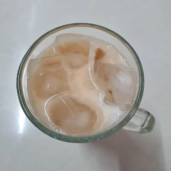 Tuang larutan air teh secukupnya. Sisa larutan dikocok kembali sampai berbusa. Ambil busa dengan sendok, taruh di atas minuman sebagai topping, sajikan.