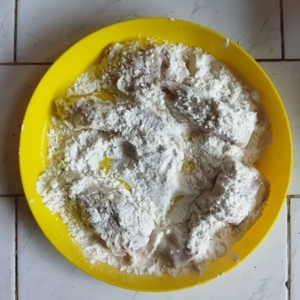 Masukkan ayam ke dalam sisa tepung serbaguna, hingga tertutup rata.