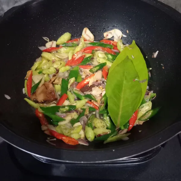 Masukkan irisan cabai, lengkuas, daun salam, dan daun jeruk lalu tumis sampai layu.