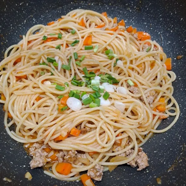 Masukkan spaghetti rebus dan daun bawang. Aduk sampai tercampur rata dengan saos. Lalu angkat dan sajikan segera.