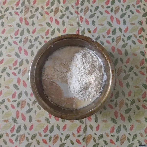 Masukkan tepung terigu, ragi instan, garam, susu bubuk dan santan, aduk kembali hingga tidak bergerindil.