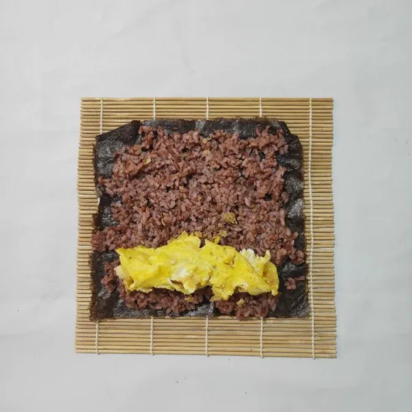 Letakkan nasi merah dan telur dadar gulung diatas nori.