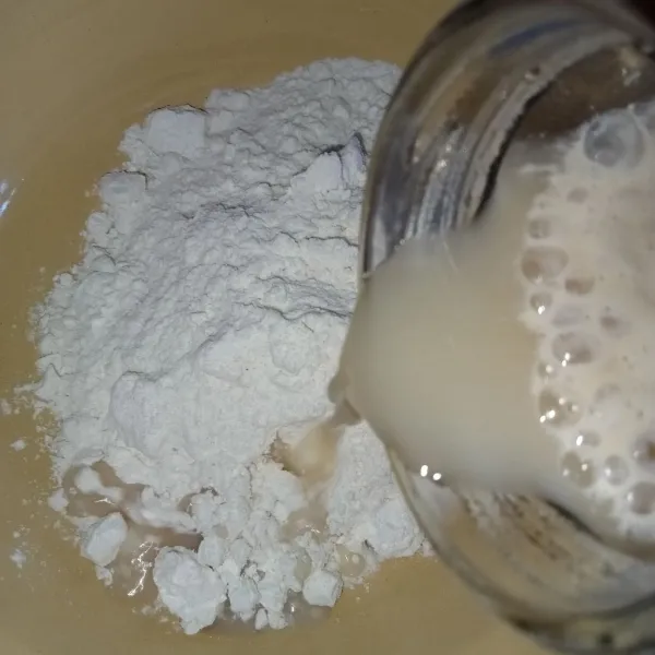 Tuang bahan biang ke dalam tepung terigu.