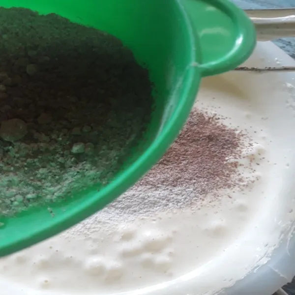 Tuang tepung terigu, baking powder, cokelat dan susu bubuk sambil diayak.