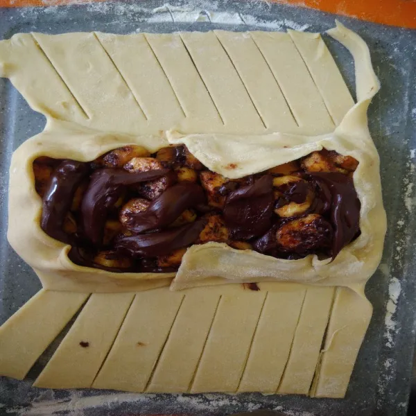 Beri isian pisang dan chocolate chip yang sudah di aduk, tambahkan chocolate filling di atasnya. Kemudian lipat kulit pastry.