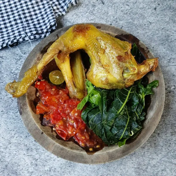 Sajikan daun pepaya rebus, ayam goreng, dan sambalnya.