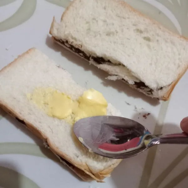 Oles margarin bagian luar roti.