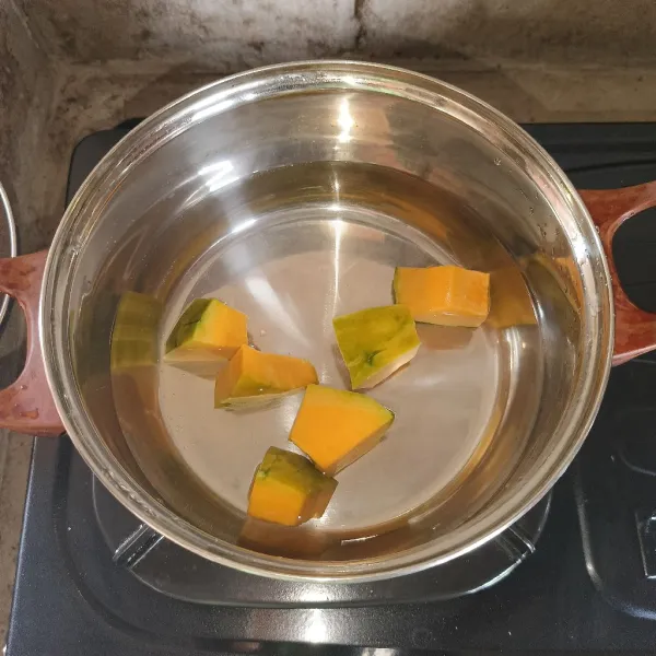 Rebus labu kuning dan air di panci.