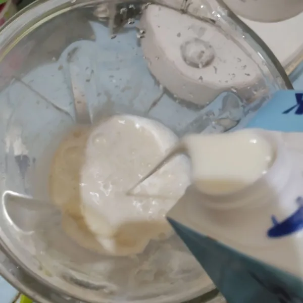 Tuang susu UHT 1 kotak dan susu kental manis ke wadah blender.