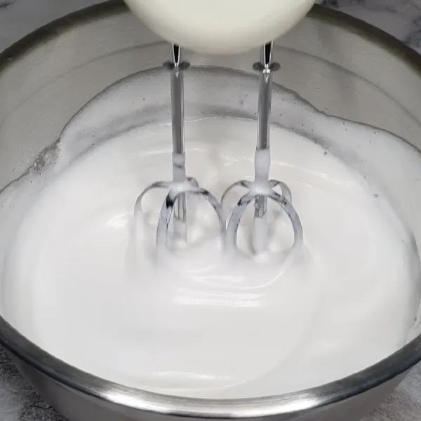 Mixer putih telur sampai berbusa. Masukkan gula halus sedikit demi sedikit sampai soft peak.