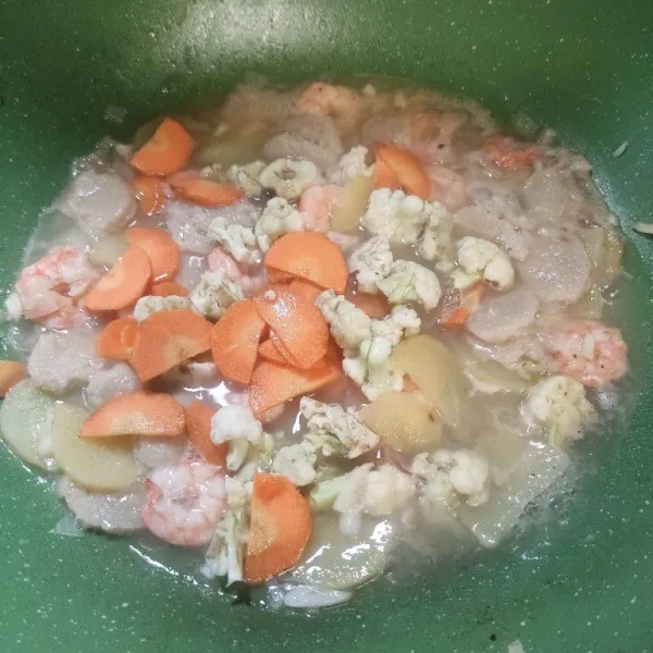 Setelah mendidih, masukkan wortel dan kembang kol, aduk dan biarkan selama 1 menit.