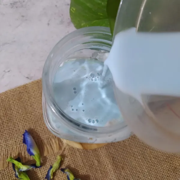 Beri aksen awan pada dinding gelas menggunakan whipped cream. Tuang susu telang perlahan ke gelas saji sampai penuh, sajikan.