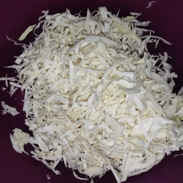 Iris tipis-tipis sayur kol dan taruh dalam wadah lalu sisihkan