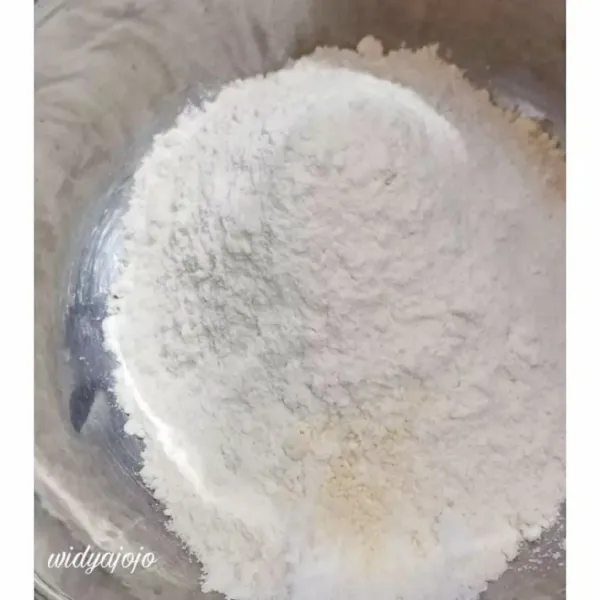 Tuang tepung terigu ke dalam mangkuk. Lalu tambahkan garam dan kaldu jamur. Aduk rata.