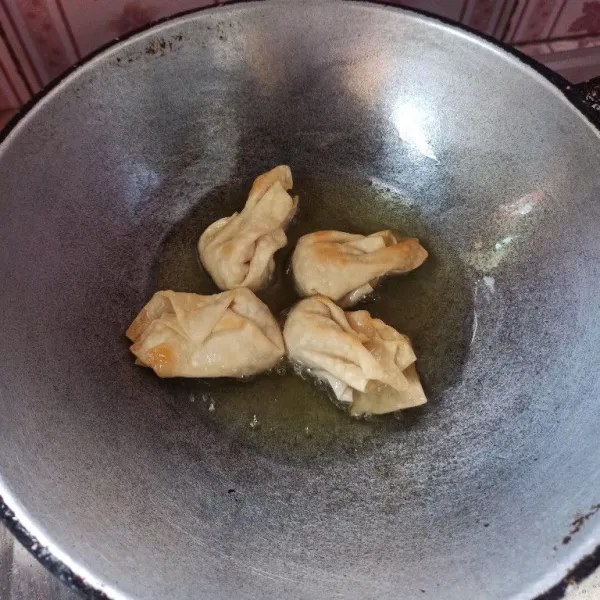 Isi kulit pangsit dengan satu sendok teh ayam kemudian lipat dan goreng hingga matang, setelah itu angkat dan tiriskan.