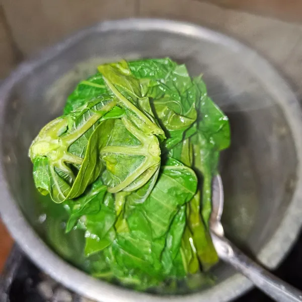 Rebus daun singkong sampai empuk, lalu tiriskan dan basuh dengan air mengalir, remas-remas  sampai asat.