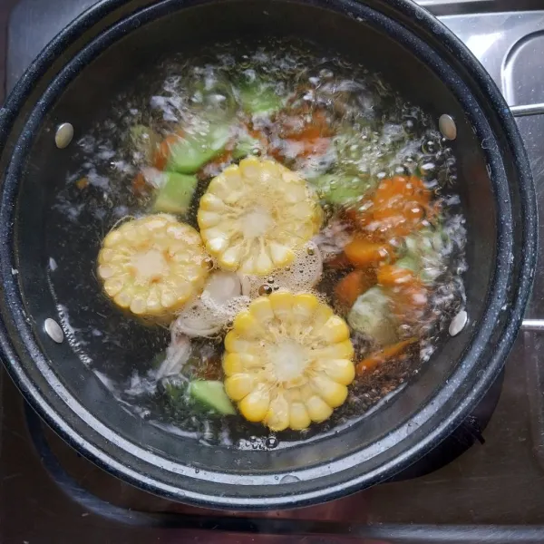 Masukkan bawang merah, jagung, wortel dan labu siam ke dalam air mendidih