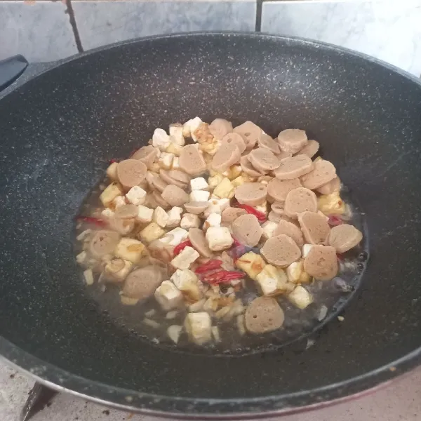 Masukkan tahu putih yang sudah digoreng dan bakso, kemudian tambahkan air. Masak hingga mendidih.