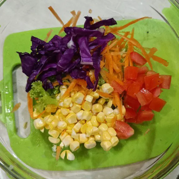 Siapkan wadah. Masukkan potongan selada, jagung pipil, irisan kol ungu, tomat, wortel. Sisihkan.
