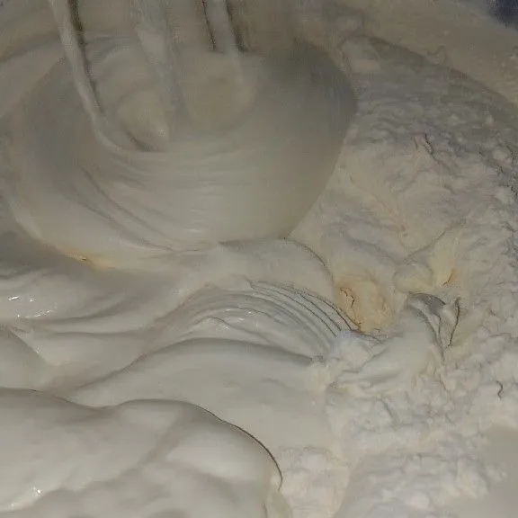 Jika adonan sudah putih kental berjejak, masukkan tepung terigu dan susu bubuk secara bertahap sambil di ayak. Lalu mixer asal tercampur rata.