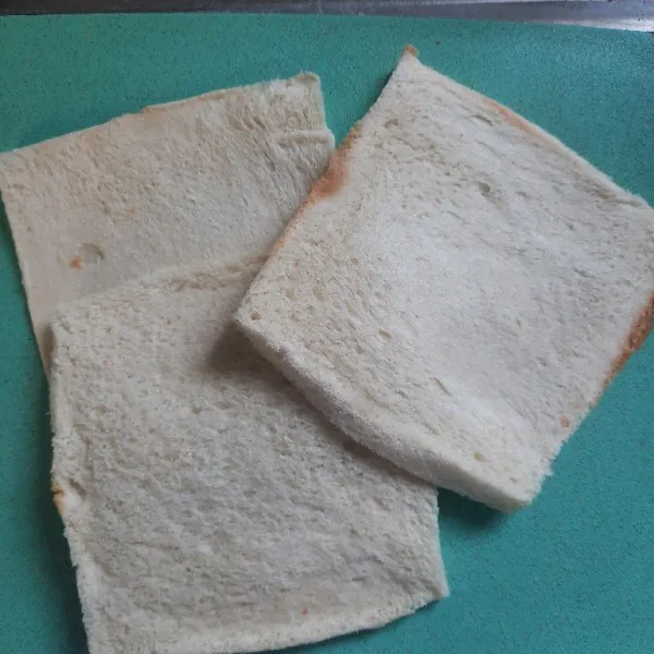 Siapkan tiga lembar roti tawar lalu gilas sampai pipih.