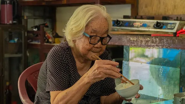 Seorang nenek sedang makan rice bowl
