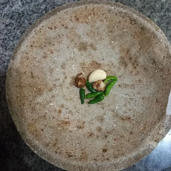 Dalam cobek tuang cabe rawit, kencur dan bawang putih.