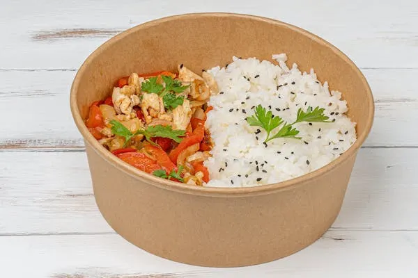 Rice bowl dengan mangkuk berwarna coklat berisi sayuran dan daging ayam serta taburan wijen hitam