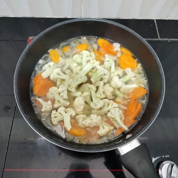 Lalu masukkan wortel dan kembang kol, masak hingga mendidih kembali.