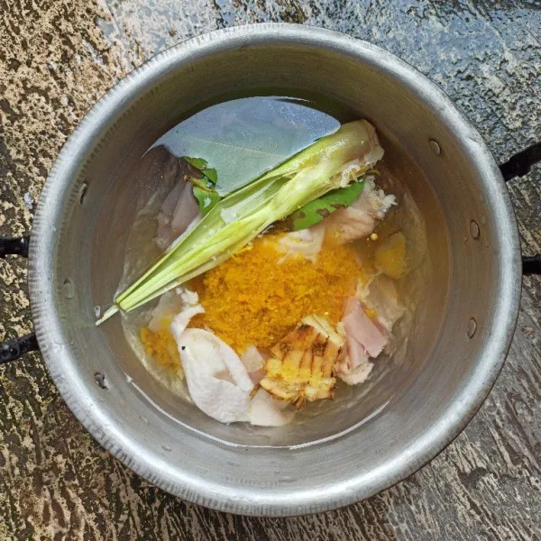 Masukkan bumbu halus, serai, daun salam dan lengkuas ke dalam panci berisi ayam dan air, rebus ayam.
