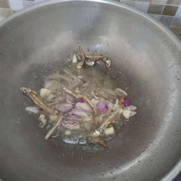 Panaskan wajan, masak ikan teri dengan bawang merah dan bawang putih hingga harum.