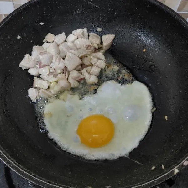 Masukkan daging ayam, aduk-aduk sampai berubah warna. Kemudian sisihkan daging ayam ke pinggir wajan, lalu masukkan 1 butir telur dan aduk cepat.
