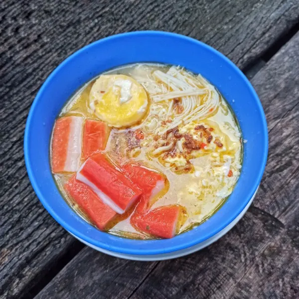 Masukkan mie, aduk rata. Beri jamur enoki, crab stick, kuning telur dan bawang goreng.