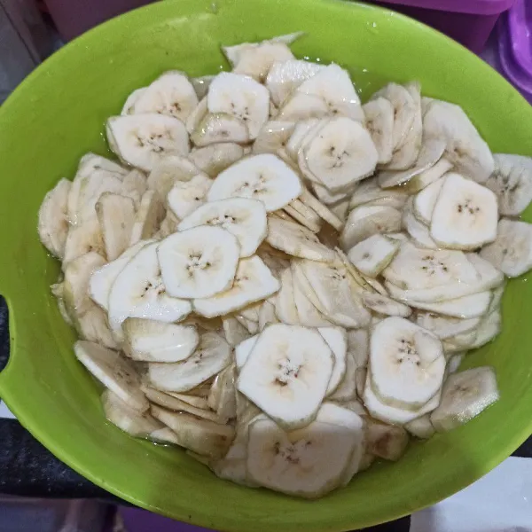 Iris pisang tipis dengan pisau atau asahan keripik (saya pakai pisau saja). Kemudian cuci bersih, lalu rendam pisang yang sudah diiris dengan garam, gula dan air selama minimal 20 menit.