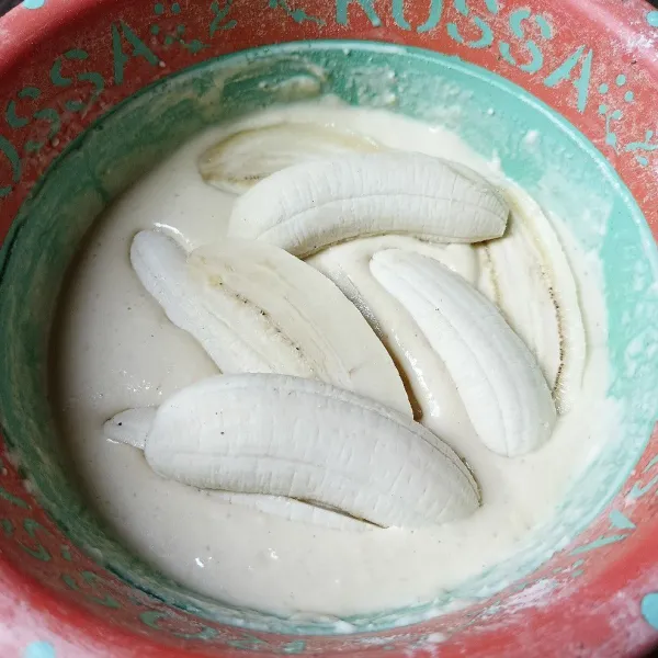 Kupas pisang dan belah dua, lalu celupkan ke dalam adonan tepung.