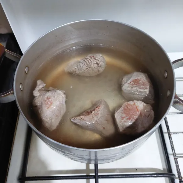 Rebus daging, buang air rebusan pertama, lalu rebus hingga setengah empuk.