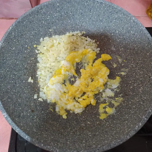 Tumis bawang bombay lalu masukkan bawang putih cincang. Setelah harum sisihkan di pinggir wajan, masukkan telur dan diorak-arik.