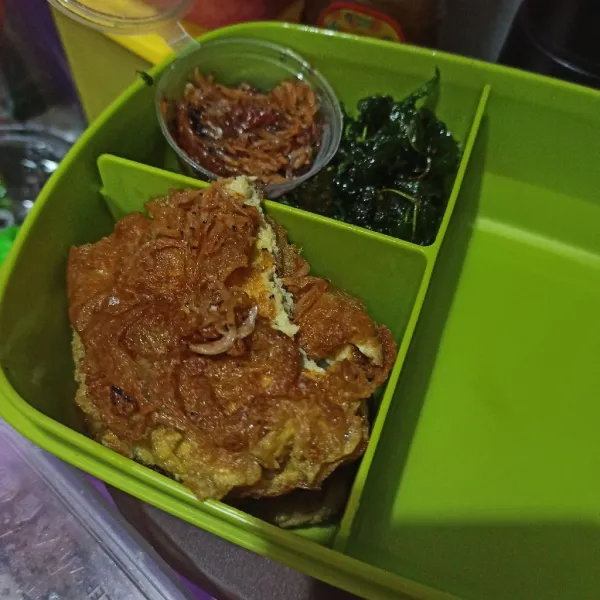 Potong telur, letakkan di dalam kotak bekal. Beri kangkung goreng dan sambal.