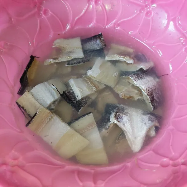 Potong-potong ikan asin gabus dan rendam di dalam air hangat sekitar 20 menit, lalu cuci bersih.
