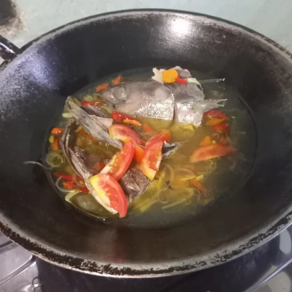 Masukkan kepala ikan. Beri bumbu garam, lada, dan kaldu bubuk. Masak hingga ikan matang. Sesaat sebelum diangkat, tambahkan tomat merah. Jangan lupa koreksi rasanya. Sajikan selagi hangat.