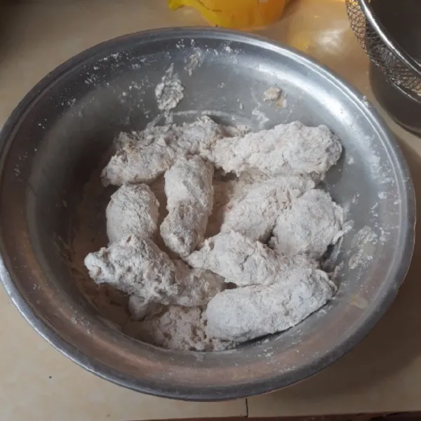 Celupkan ayam ke lapisan basah, baluri dengan tepung, celupkan lagi ke lapisan basah dan baluri lagi dengan tepung.