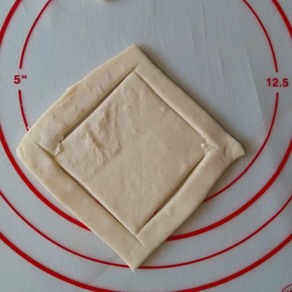 Potong puff pastry menjadi 4 bagian, lalu potong persegi pada bagian dalam puff.