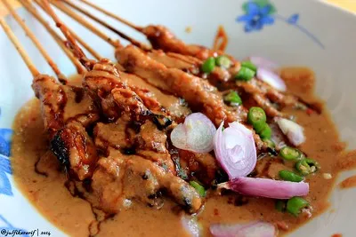 Sate kelinci berbumbu kacang dengan taburan bawang, cabai, serta kecap