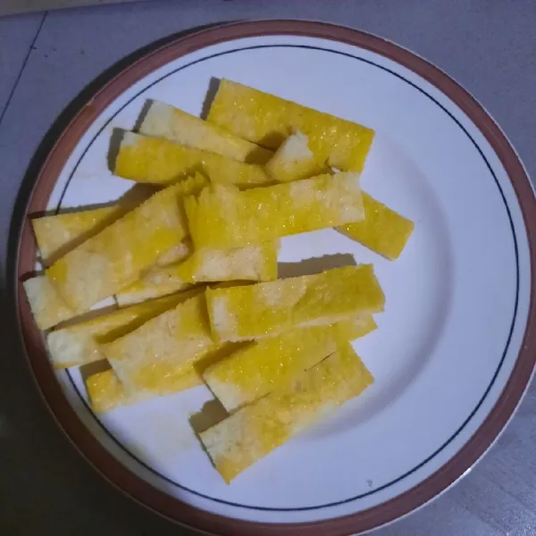 Oles permukaan roti tawar dengan margarin dikedua sisinya.