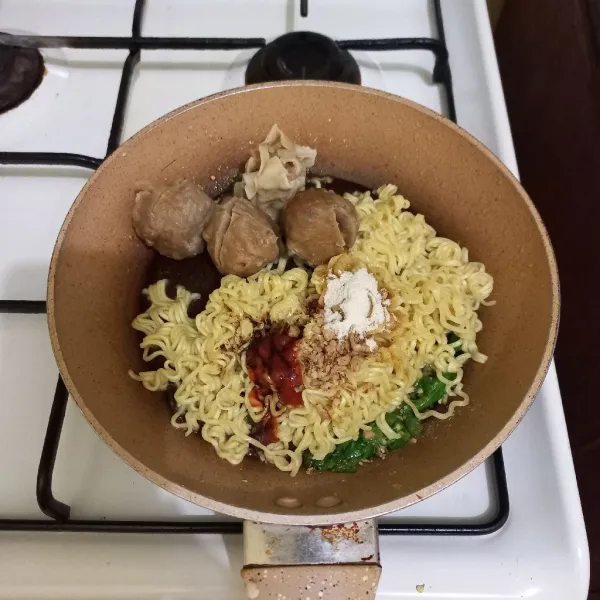 Beri bumbu pelengkap mie goreng, aduk rata. Masak hingga matang.