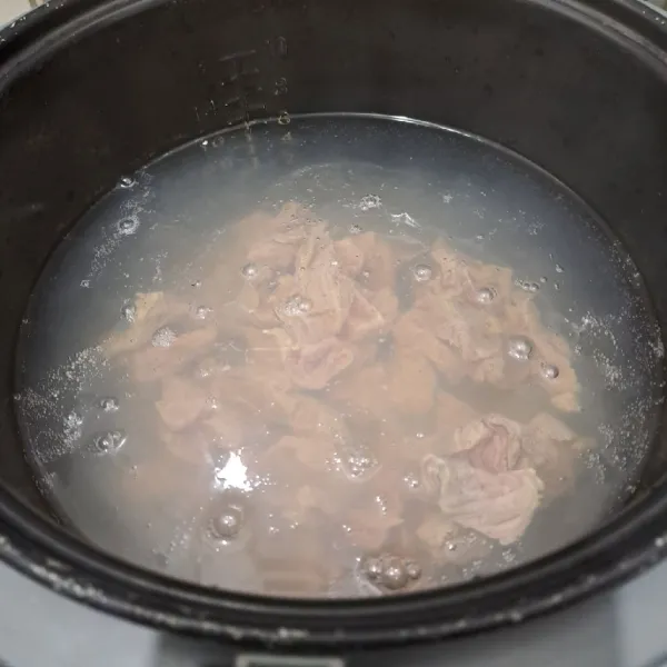 Masukkan air dalam rice cooker. Pencet cook sampai air mendidih. Masukkan potongan daging. Tutup lagi rice cooker sambil menyiapkan bumbu.